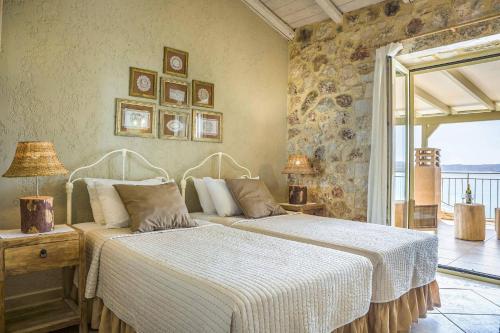two beds in a bedroom with a stone wall at Villa Kalou Cottage by Villa Plus in Mousata