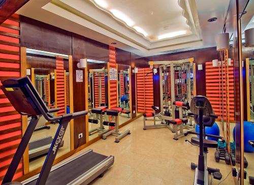 - une salle de sport avec plusieurs tapis de course et machines dans l'établissement Sarovar Portico Rivera Ahmedabad, à Ahmedabad