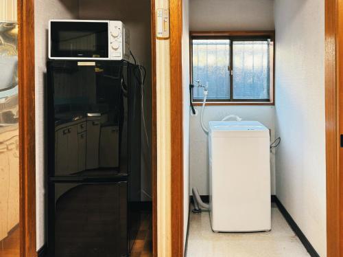 a small kitchen with a microwave and a refrigerator at #12 -関ヶ原 蛍- 古民家の宿 in Sekigahara