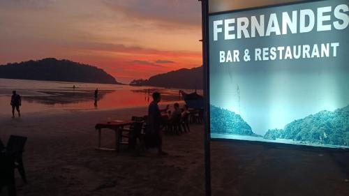 a sign on a beach with at Fernandes Bar and Restaurant in Canacona