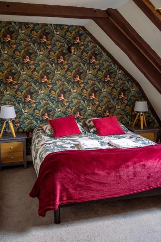 a bedroom with a bed with red pillows and a floral wall at Domaine de Cantelou in Clécy