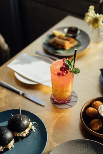 a wooden table with plates of food and a drink at ME Malta by Meliá in St Julian's