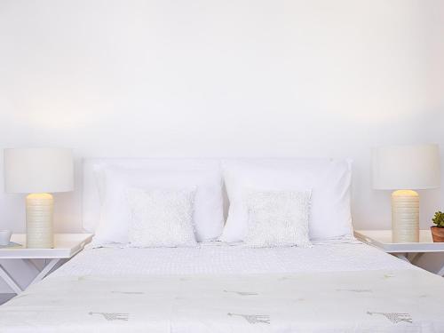 a white bed with white pillows and two lamps at Grecotel Meli Palace in Sissi