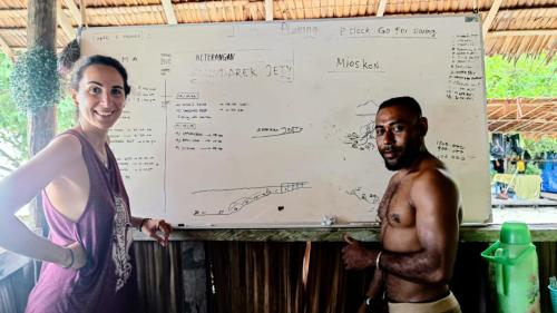 a woman and a man standing in front of a whiteboard at Daroyen Village in Kri