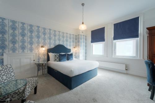 a bedroom with a bed and a chair and windows at Florence Gardens Boutique Hotel and Restaurant in Portsmouth