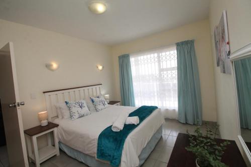 a bedroom with a bed and a window with blue curtains at Michael Point 6 in Shelly Beach