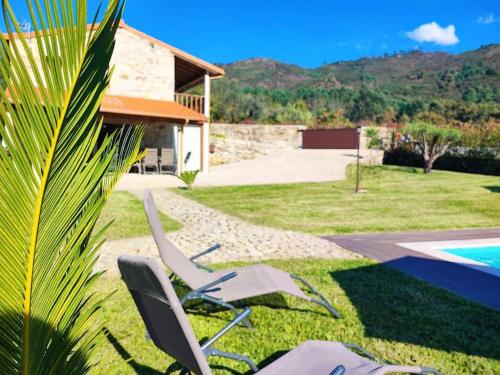 a yard with two chairs and a swimming pool at Casa doNegrinho com Piscina in Monção