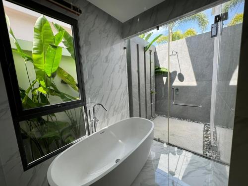 une baignoire blanche dans une salle de bains avec fenêtre dans l'établissement Luxury Breeze Villa with private pool & maid, à Ban Thalat Choeng Thale
