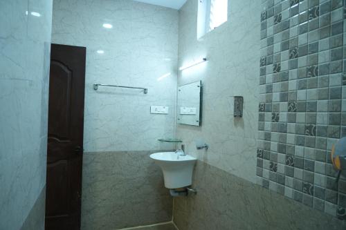 a bathroom with a sink and a mirror at Sri Krishnan Residency in Pollāchi