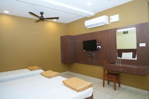 a bathroom with two beds and a sink and a mirror at Sri Krishnan Residency in Pollāchi