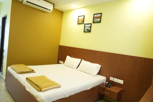 a bedroom with a bed with white sheets and yellow walls at Sri Krishnan Residency in Pollāchi