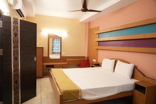 a bedroom with a bed and a desk with a mirror at Sri Krishnan Residency in Pollāchi