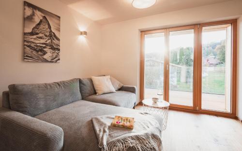 a living room with a couch and a large window at Benedikt & Wilhelmine in Rettenberg