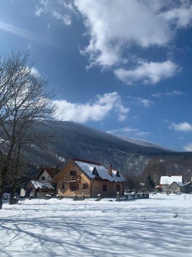 a log cabin with snow on the ground in a field at Kuća za odmor Petra in Jasenak