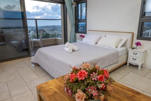 a bedroom with a bed and a table with flowers on it at אחוזת כנען - וילה מדהימה עם בריכה פרטית מחוממת וג'קוזי in Yarka