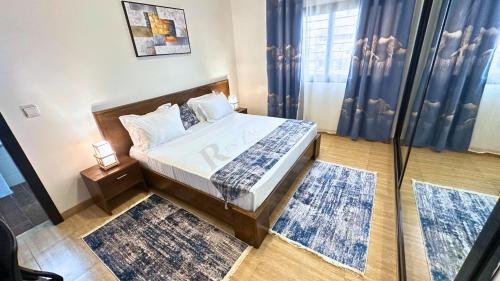 a bedroom with a bed with blue curtains and rugs at Res'Zac in Rufisque