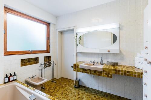 une salle de bain avec deux lavabos, une baignoire et un miroir dans l'établissement Mélodie Mosellane - Charmant appt avec jardin, à Metz
