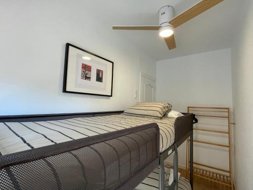 a bedroom with a bed and a ceiling fan at Ático a 15 min en tren del centro in Sant Adria de Besos