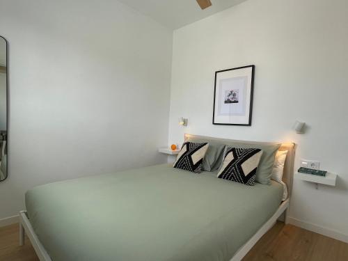 a white bedroom with a large bed with two pillows at Ático a 15 min en tren del centro in Sant Adria de Besos