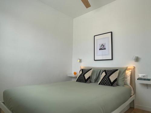 a bedroom with a bed with a white wall at Ático a 15 min en tren del centro in Sant Adria de Besos