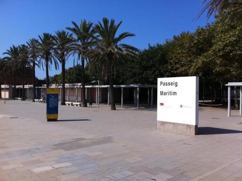 a sign in a parking lot with palm trees at Ático a 15 min en tren del centro in Sant Adria de Besos
