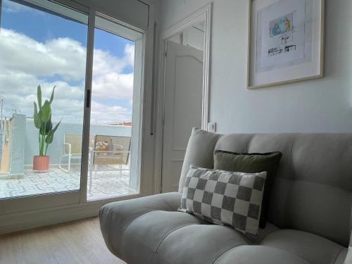 a living room with a couch and a sliding glass door at Ático a 15 min en tren del centro in Sant Adria de Besos