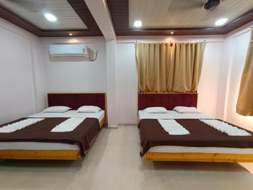 two beds sitting in a room with at Hotel Town Pride , Ganpatipule in Ganpatipule