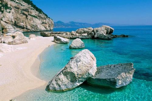 un gruppo di rocce nell'acqua su una spiaggia di Apartment Conchiglie a Cala Gonone