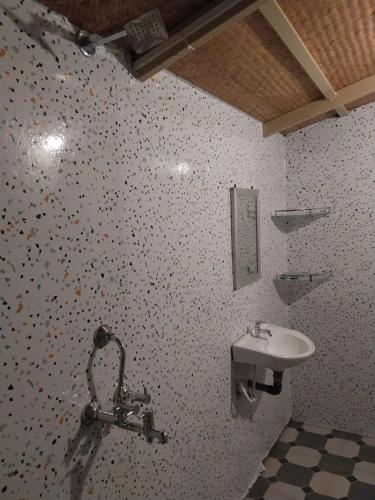 bagno con lavandino e parete piastrellata di Fernandes Bar and Restaurant a Canacona