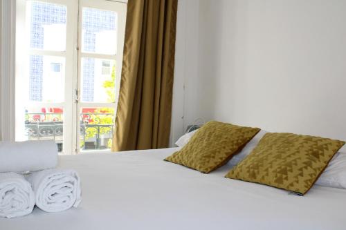 a white bed with two pillows and a window at Urban City in Aveiro