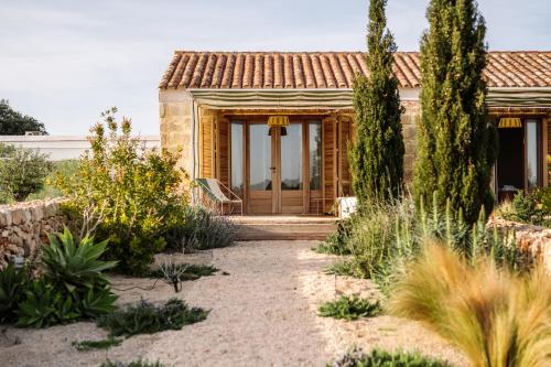 a house with a wooden door in a garden at Amagatay Luxury Boutique Hotel - Adults Only in Alaior