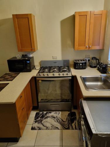 a kitchen with a stove and a sink at Charming 2-Bed House in Portmore gated community in Portmore