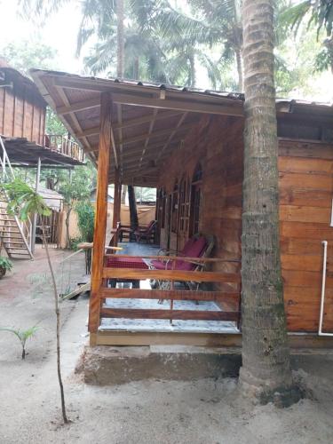a wooden cabin with a porch with a palm tree at Fernandes Bar and Restaurant in Canacona