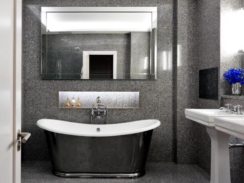 a bathroom with a large tub and a sink at Haymarket Hotel, Firmdale Hotels in London