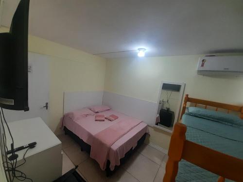 a small bedroom with a pink bed and a television at Pousada cafe com margarida 150 metros do mar rua do calçadao da central in Balneário Camboriú