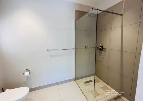 a glass shower in a bathroom with a toilet at The Franklyn Parkview in Johannesburg