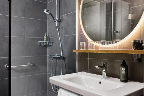 a bathroom with a sink and a shower at H2 Hotel Saarbrücken in Saarbrücken