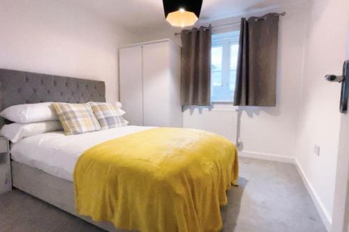 a bedroom with a bed with a yellow blanket on it at Fabulous 2bedroom flat in Coventry