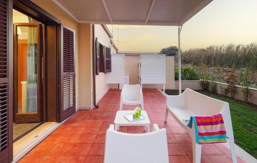 eine Terrasse mit weißen Stühlen und einem Sonnenschirm in der Unterkunft 2 Bedroom Amazing Home In Marina Di Modica in Marina di Modica