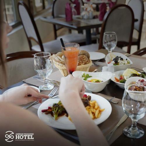 a person sitting at a table with plates of food at Amman Paradise Hotel in Amman