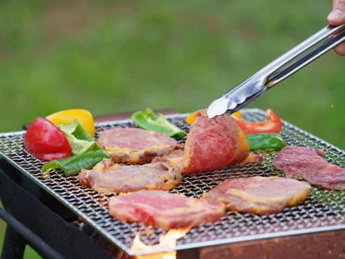 a person is cooking meat and vegetables on a grill at Nature Miraikan in Naha