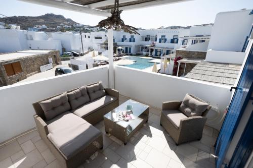 a balcony with couches and a table and chairs at Blue, White and Grey Suites in Ornos