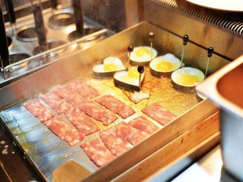 a grill with meat and other food on it at Metropolo Hotel Qingdao Wusi Square Xiaomaidao in Qingdao