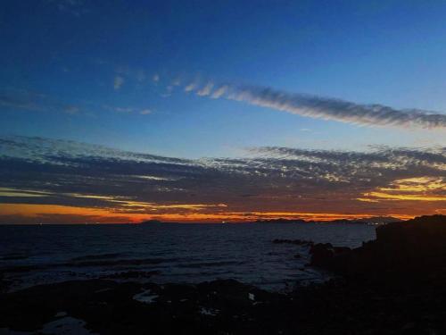 a sunset over the ocean with a cloudy sky at Metropolo Hotel Qingdao Wusi Square Xiaomaidao in Qingdao