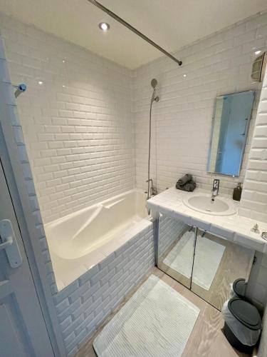une salle de bain blanche avec une baignoire et un lavabo dans l'établissement Tour Eiffel - Motte Picquet, à Paris