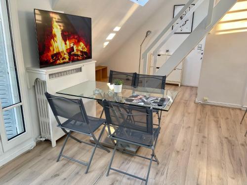 une salle à manger avec une table et des chaises en verre ainsi qu'une télévision dans l'établissement Tour Eiffel - Motte Picquet, à Paris