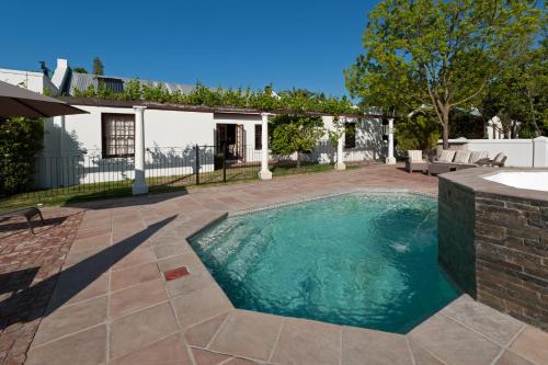 a swimming pool in a yard next to a house at La Galiniere Guest Cottages in Franschhoek