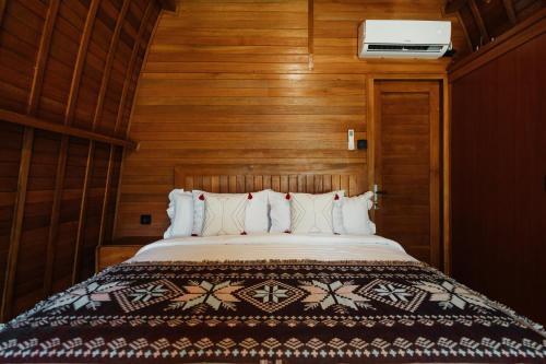 a bed in a room with wooden walls at Maha Villa Kelating in Krambitan