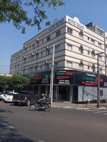 a man riding a motorcycle in front of a hotel building at Hotel Globo in Cianorte