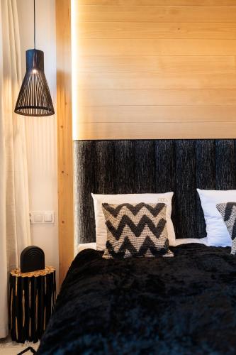 a bedroom with a black bed with a wooden headboard at Stylchyn Park - Czorsztyn Exclusive - by Upstairs in Kluszkowce